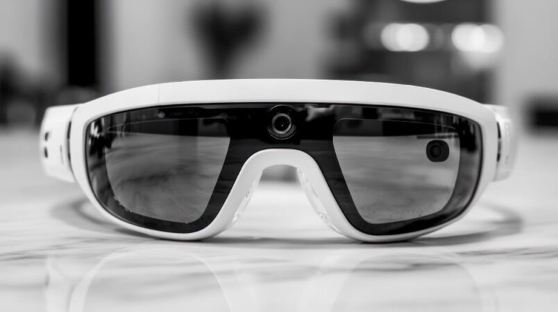 Image en noir et blanc de face montrant une paire de lunettes espion blanches avec des caméras intégrées