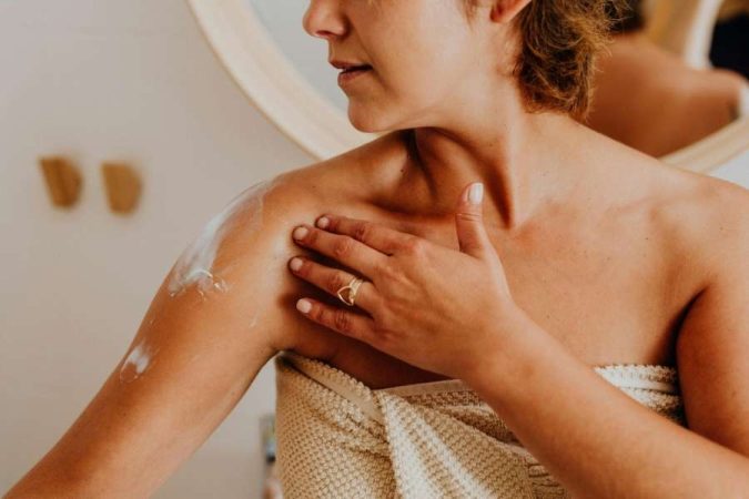 Une femme applique une crème hydratante pour hydrater le corps après la douche.